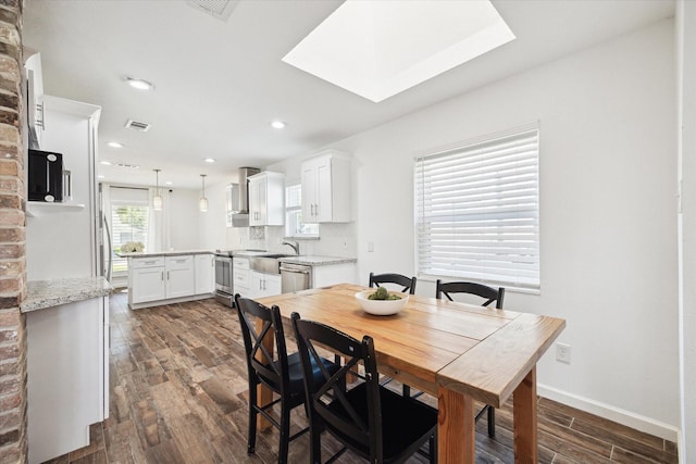 dining room featuring visible vents, baseboards, dark wood-style floors, and a skylight