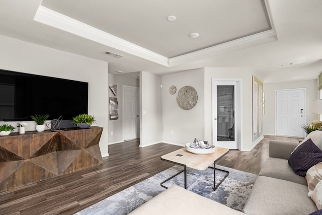 living room featuring a raised ceiling, wood finished floors, visible vents, and crown molding