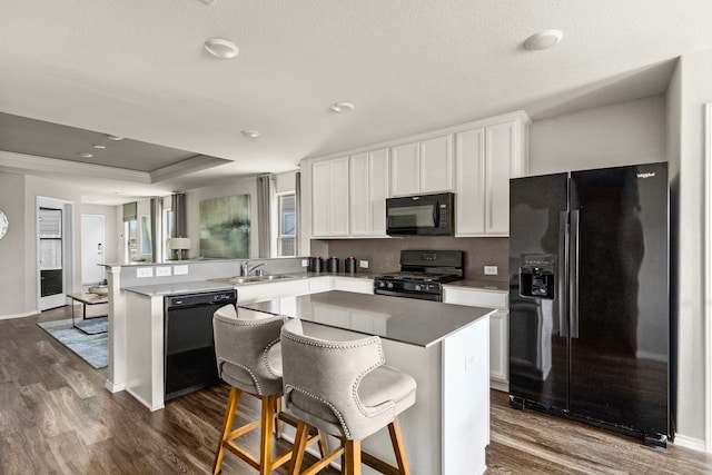 kitchen with a sink, white cabinetry, black appliances, and dark wood finished floors