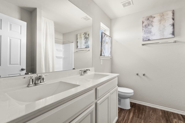 bathroom with a shower with shower curtain, wood finished floors, visible vents, and a sink