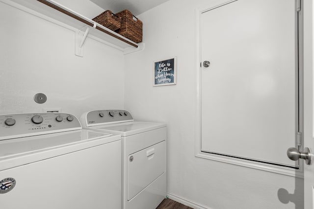 clothes washing area with separate washer and dryer, wood finished floors, and laundry area