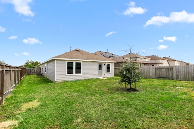 back of property with a yard, a fenced backyard, and central AC unit