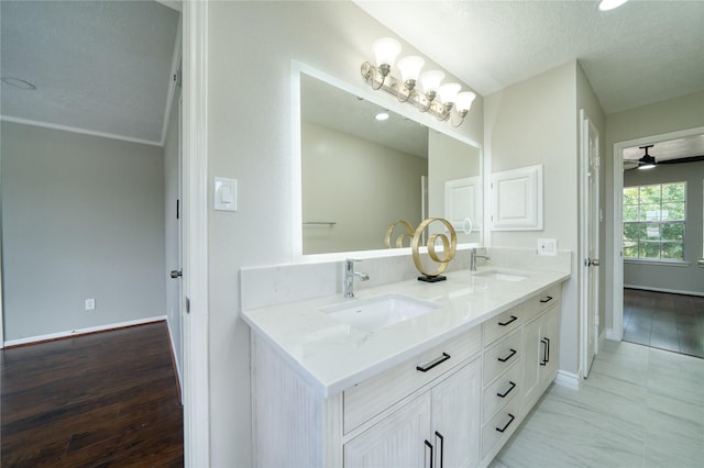 bathroom with baseboards, a sink, a textured ceiling, and double vanity