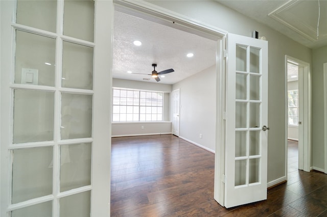 empty room with attic access, a textured ceiling, baseboards, and dark wood-style flooring