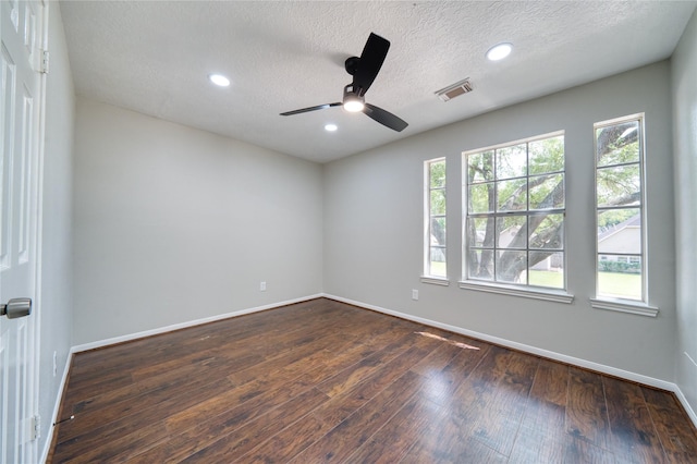 spare room featuring dark wood-style floors, a textured ceiling, baseboards, visible vents, and a ceiling fan
