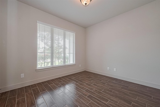 unfurnished room featuring baseboards and dark wood-type flooring