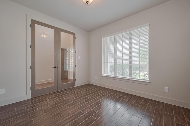 empty room featuring baseboards, french doors, and dark wood-style floors