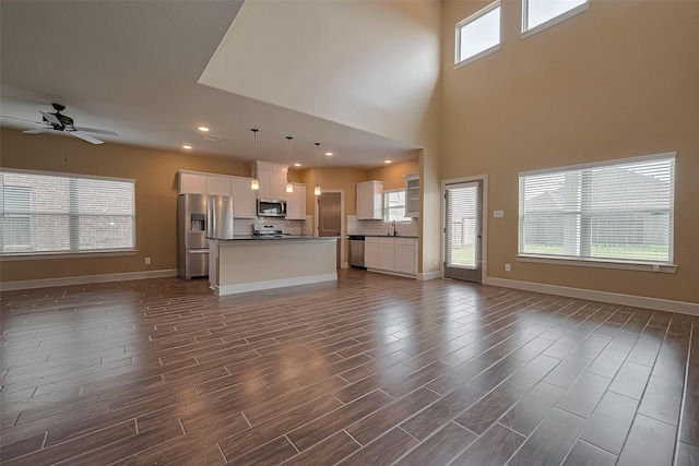 unfurnished living room with a sink, dark wood finished floors, baseboards, recessed lighting, and a ceiling fan