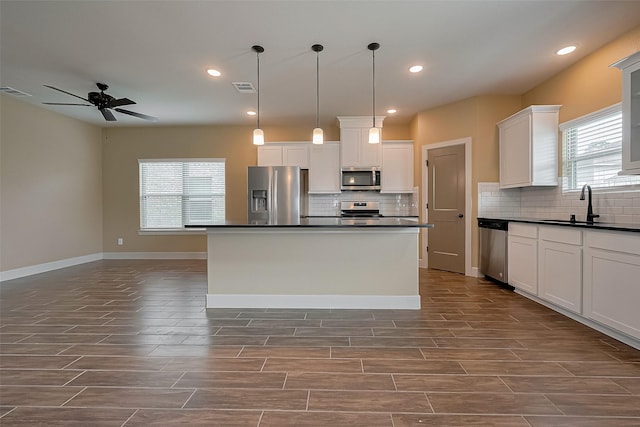 kitchen featuring stainless steel appliances, visible vents, a sink, and dark countertops