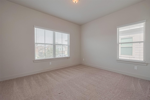 empty room featuring baseboards and light colored carpet