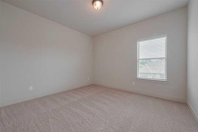 spare room featuring baseboards and light colored carpet