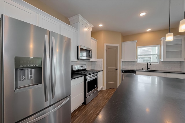 kitchen featuring dark countertops, a sink, decorative backsplash, white cabinetry, and appliances with stainless steel finishes