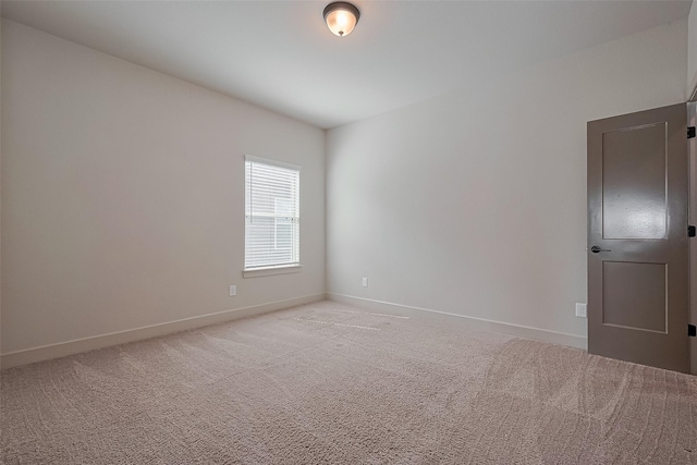 spare room with baseboards and light carpet