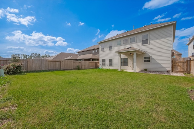 back of house with a fenced backyard and a yard