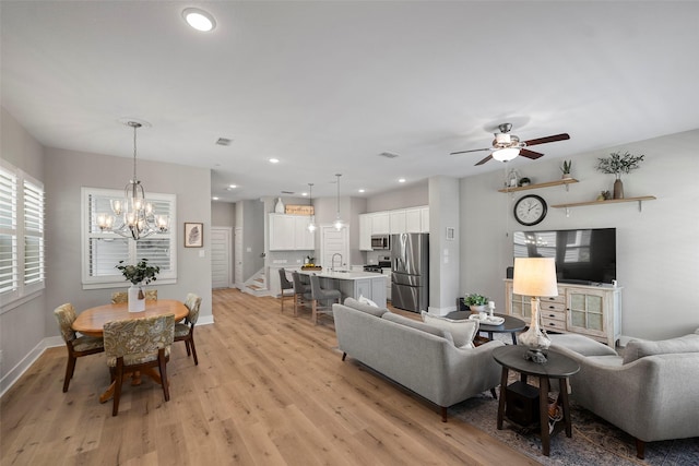 18611 Admiration Dr, Cypress, TX 77433 - living room featuring visible vents, light wood-type flooring, baseboards, stairs, and ceiling fan with notable chandelier