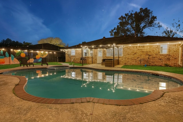 pool at twilight featuring fence, a patio, and a pool with connected hot tub