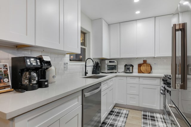 kitchen featuring white cabinets, stainless steel dishwasher, decorative backsplash, and a sink