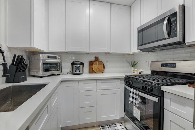 kitchen featuring decorative backsplash, white cabinetry, and stainless steel appliances