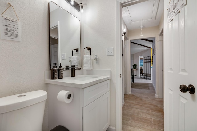 bathroom featuring a textured wall, wood finished floors, vanity, and toilet