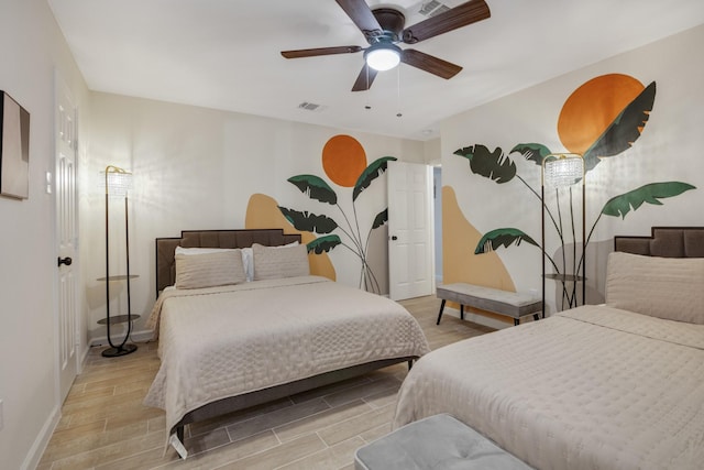 bedroom with ceiling fan, wood finish floors, visible vents, and baseboards