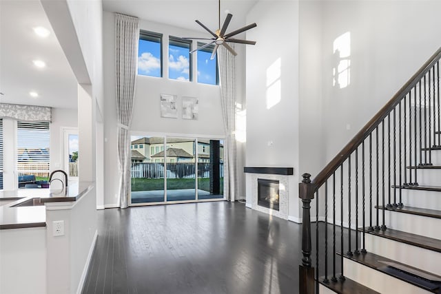 entrance foyer featuring a glass covered fireplace, plenty of natural light, a high ceiling, and a ceiling fan