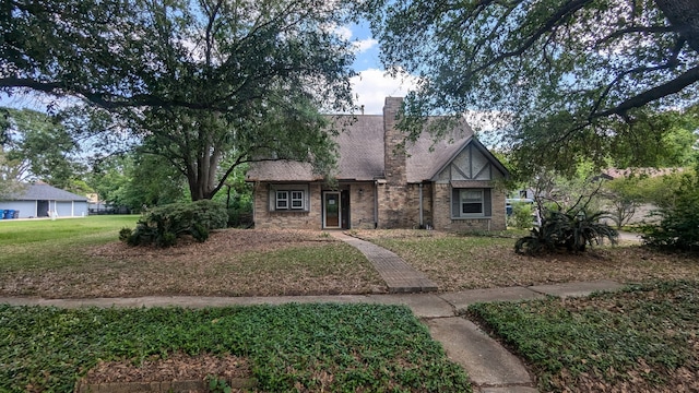 english style home featuring a chimney and a front lawn