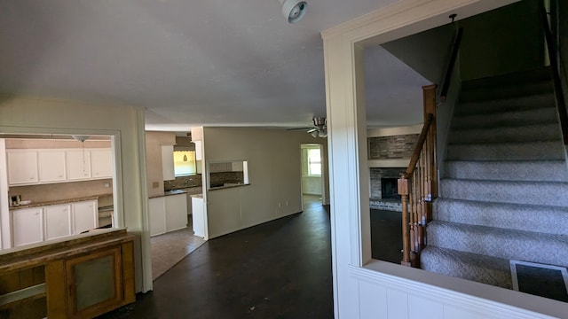 staircase with a ceiling fan and a fireplace
