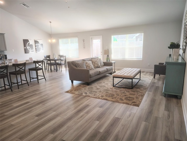 15 Gemstone Ct, Angleton, TX 77515 - living room featuring lofted ceiling, wood finished floors, visible vents, and an inviting chandelier