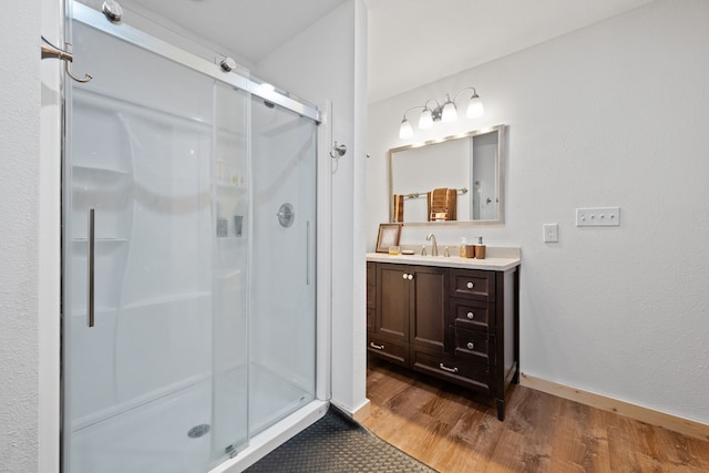 full bathroom featuring baseboards, vanity, wood finished floors, and a shower stall