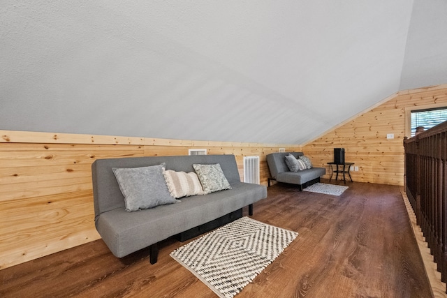 interior space featuring lofted ceiling, wood walls, wood finished floors, and visible vents