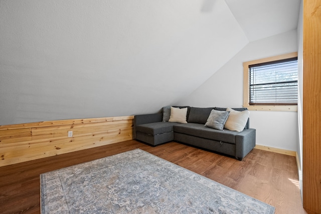 living room featuring lofted ceiling, wood finished floors, and baseboards