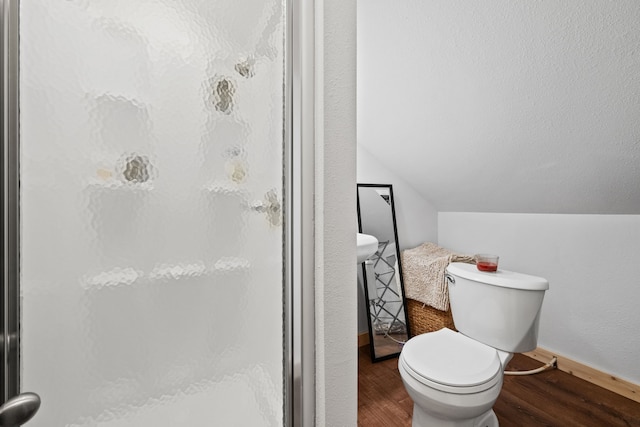 bathroom with baseboards, wood finished floors, a shower stall, and toilet