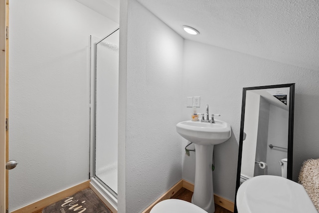 bathroom with toilet, wood finished floors, a textured ceiling, and a stall shower