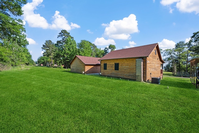 rear view of house featuring a shingled roof, a yard, and cooling unit
