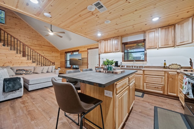 kitchen with wooden walls, visible vents, light brown cabinets, wood ceiling, and a kitchen bar