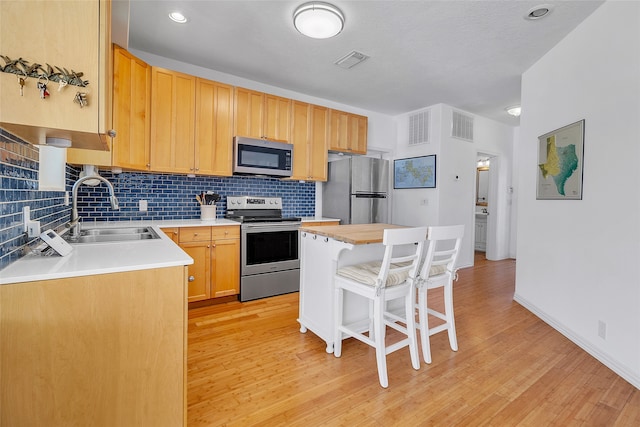kitchen with a kitchen bar, tasteful backsplash, stainless steel appliances, and a sink