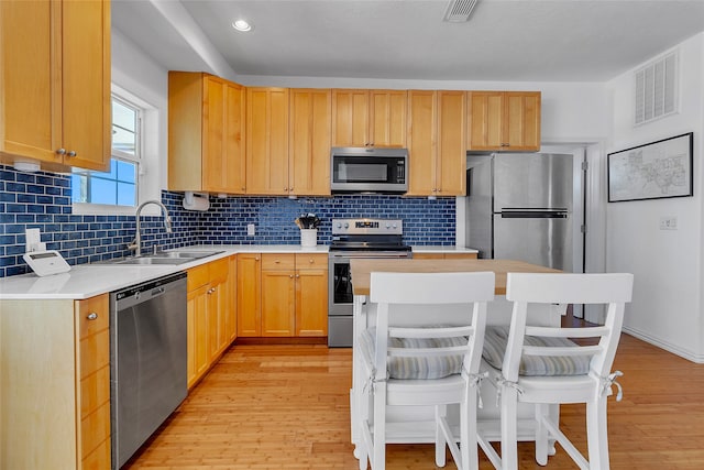 kitchen featuring stainless steel appliances, light countertops, visible vents, a sink, and light wood-style floors