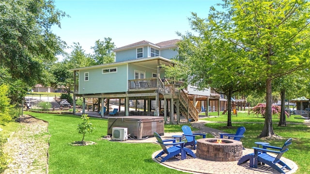 back of house featuring a patio area, a lawn, a hot tub, stairs, and an outdoor fire pit
