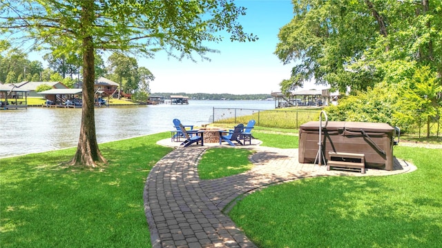 exterior space with a yard, a water view, a patio, an outdoor fire pit, and a hot tub
