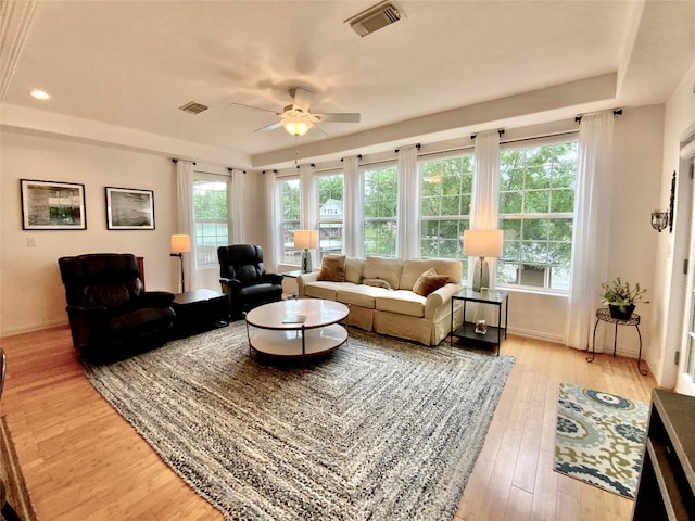 living room featuring visible vents, light wood finished floors, baseboards, and ceiling fan