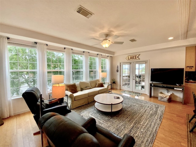 living room with a ceiling fan, visible vents, and light wood-style floors
