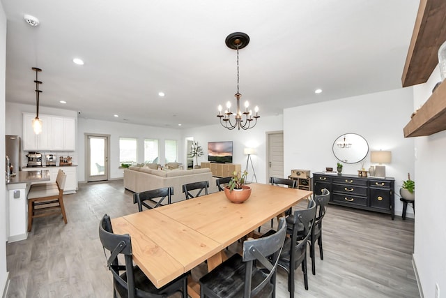 dining area with recessed lighting, light wood-style flooring, baseboards, and a notable chandelier