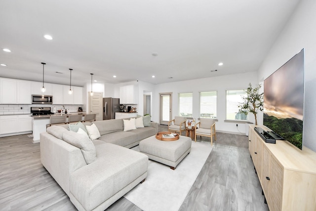 living area with baseboards, light wood finished floors, and recessed lighting