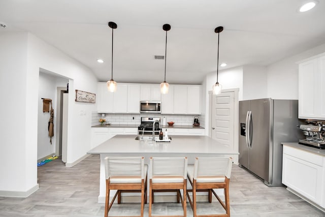 kitchen with backsplash, appliances with stainless steel finishes, a center island with sink, a sink, and white cabinets