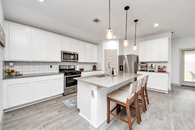 kitchen with backsplash, appliances with stainless steel finishes, light wood-type flooring, a sink, and recessed lighting