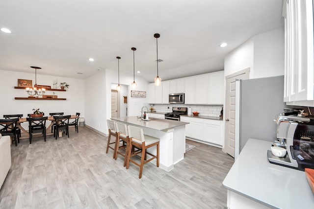 kitchen with an inviting chandelier, recessed lighting, a sink, backsplash, and stainless steel appliances