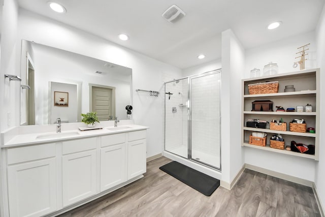 bathroom with wood finished floors, visible vents, a sink, and a stall shower