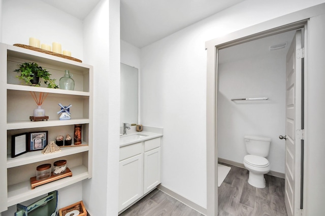 bathroom with toilet, wood finished floors, and vanity