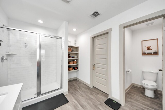 bathroom featuring a shower stall, wood finished floors, and visible vents