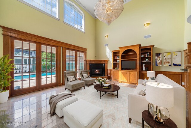 1002 Island Vw, League City, TX 77565 - living room with visible vents, a glass covered fireplace, a towering ceiling, and an inviting chandelier
